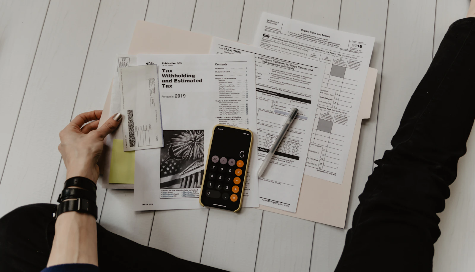A notebook, pen and coins arranged on a wooden desk for household budget planning